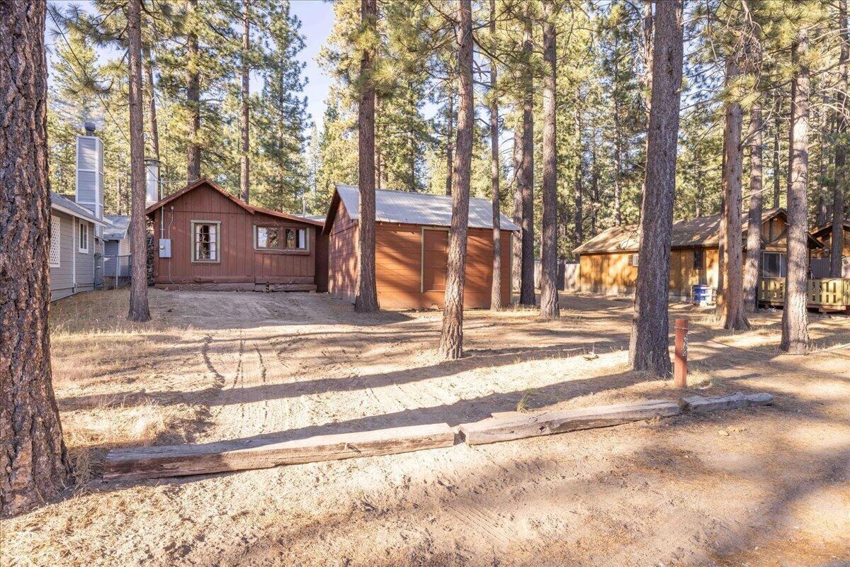 520 W Aeroplane Blvd, Big Bear City — vintage cabin and outbuildings on a level, treed lot beneath tall pines