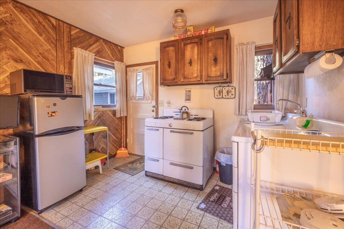 Vintage kitchen with original wood cabinetry, white range, and tile floor