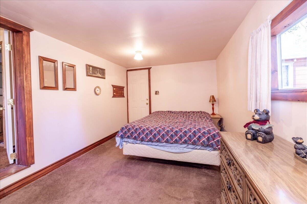 Bedroom with bed, dresser, and windows looking into the trees